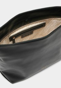 Bolso de cuero negro con acabado texturizado, forro beige con estampado, bolsillo con cremallera y detalle de logo en el interior.