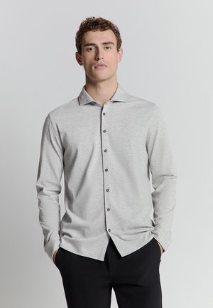Hellgraues, langärmliges Hemd mit Knopfleiste, weichem Textil, klassischem Kragen und dunklen Knöpfen auf der Vorderseite, kombiniert mit schwarzen Hosen.