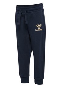 Pantalons de survêtement navy en tissu doux avec un cordon de serrage à la taille et aux poignets. Doté d'un logo doré "hummel" sur la cuisse gauche.