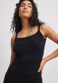 Black, sleeveless fuzzy knit dress with a square neckline and fitted silhouette. Soft texture, minimal design, and no visible patterns.