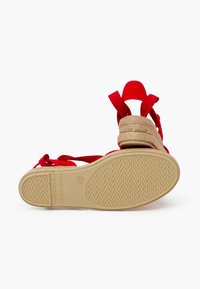 Sandalia roja con tacón de esparto trenzado y correas elásticas. Presenta una suela de goma texturizada en color marrón. Hecho en España. Talla 32.