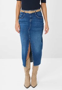 Denim midi-jurk in donkerblauw met een voorknos en een rafelige zoom, gecombineerd met een tan kleurige riem en beige enkelboots met spitse neuzen.