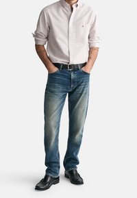 Rutiga skjortor i nyanser av röd och vit, kombinerat med bleknade blå denimjeans och svarta läderskor.