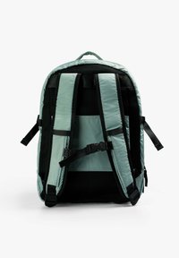 Mochila con un exterior de nylon verde menta, correas almohadilladas de malla negra, hebilla ajustable y un amplio compartimento principal. Acentos ergonómicos oscuros.
