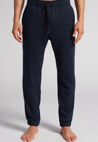 Marineblauwe joggers van zachte stof, voorzien van een elastische tailleband met trekkoord en elastische boorden op de enkels.