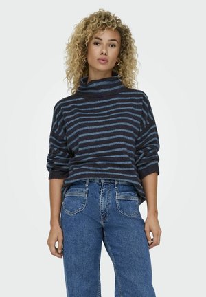 Navy blue striped turtleneck sweater with wide sleeves, ribbed cuffs, and a relaxed fit, paired with high-waisted blue jeans.
