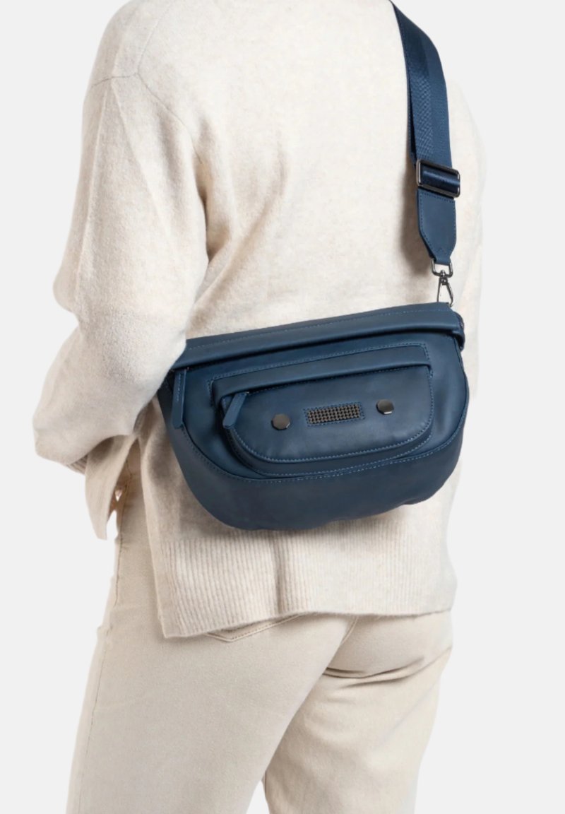 Donkerblauwe leren schoudertas met een gemarmerde voorzijde, ritssluiting en verstelbare strap, gedragen over een beige trui.