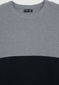 Szary i czarny sweter o fakturowanym wykończeniu, z okrągłym dekoltem i poziomym wzorem kolorowych bloków. Metka oznaczona "Terranova XL."