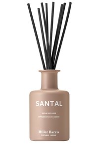 Santal-Raumd diffuser in einer matten, beigen Glasflasche, ausgestattet mit schwarzen Rattanstäbchen und weißem Text, der die Marke und Produktbeschreibung angibt.