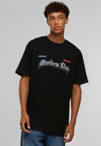 Sort bomulds t-shirt med korte ærmer, prydet med "Members Only" tekst i en stilfuld skrifttype og farverige accenter på venstre bryst.