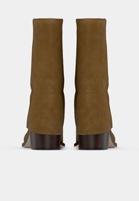 Barna velúr bokacsizmák sima felülettel, fából készült sarokkal és egyszerű dizájnnal, amelyen nincsenek látható minták vagy díszítések.