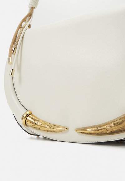 White leather shoulder bag featuring gold-tone horn accents, smooth texture, and a structured design with a curved silhouette.