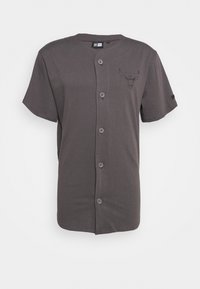 Šedá košile na krátký rukáv z měkké látky, s jemným logem býka vytištěným na levé straně hrudi a pěti knoflíky vpředu.