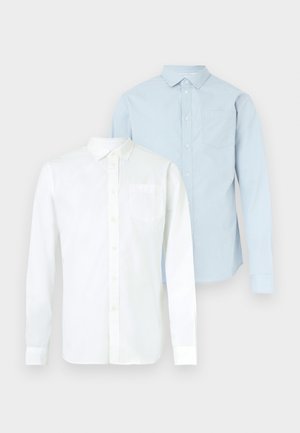 Dvi ilgomis rankovėmis marškiniai: vieni balti, kiti šviesiai mėlyni su mažais taškeliais. Abu turi apykakles su sagomis ir krūtinės kišenes.