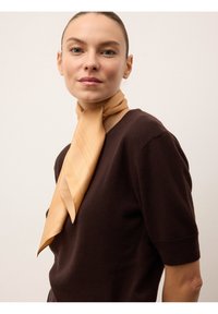 Pull marron à manches courtes avec une écharpe beige clair nouée autour du cou, présentant de légères rayures verticales et une texture lisse.