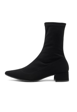 Black ankle boot made of stretchy fabric features a pointed toe, short block heel, and a fitted shaft with contrasting stitching details.