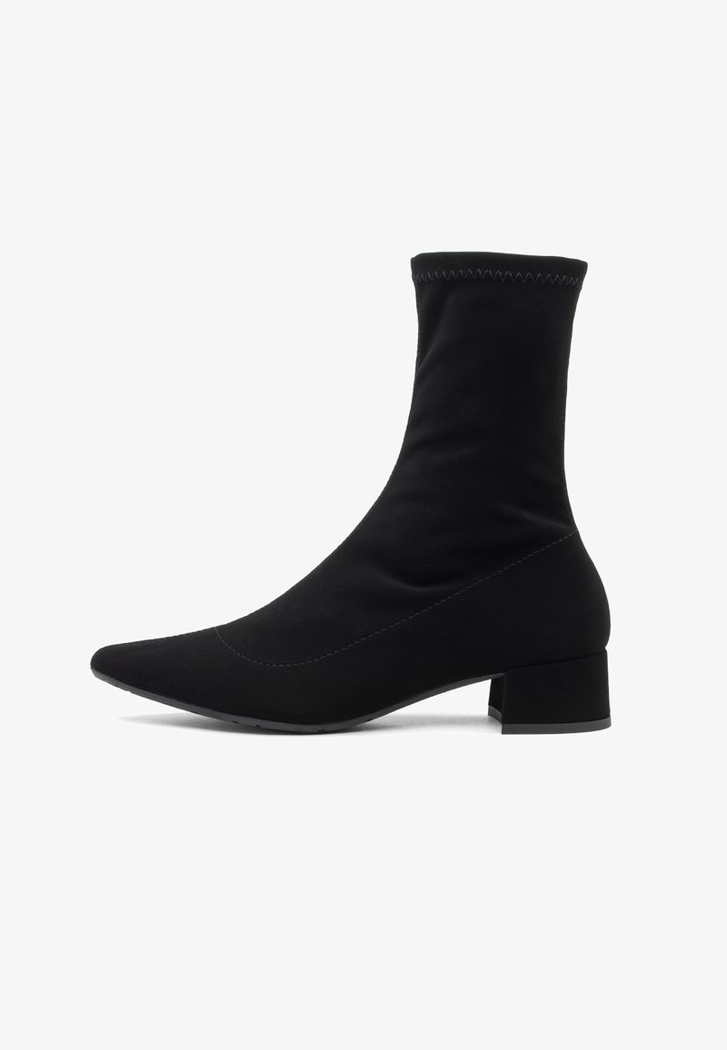 Črne gležnjarje iz raztegljivega blaga odlikujeta koničast nos in kratek blokast petek, prilegajoča se zgornja del pa ima kontrastne šive.