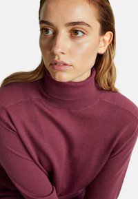 Sweter z golfem w kolorze burgundowym, z prążkowanym kołnierzem, miękką fakturą i dopasowanym krojem, prezentujący gładki materiał bez wzorów.