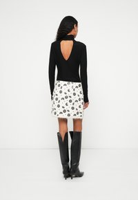 Fekete hosszú ujjú felső hátul kivágással, fehér szoknyával, amely fekete virágmintákkal díszített. Térdig érő fekete, magassarkú csizma.