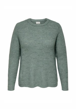 Světle zelený pletený svetr s kulatým výstřihem, dlouhými rukávy a strukturovaným vzorem hexagonů. Detail zvlněného lemu na spodním okraji.