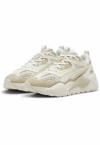 Zapatillas blancas y crema con detalles de malla y gamuza, que cuentan con una suela gruesa, detalles texturizados y un sistema de cordones para un ajuste perfecto.