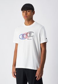 Camiseta de algodón blanca con un gráfico colorido del logo de Champion en azul, rojo y negro. Manga corta y cuello redondo.