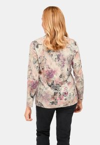 Blumenmuster Langarmshirt in Pastellfarben mit schwarzen Akzenten, aus weichem Stoff und detaillierten Blumenmustern über das gesamte Shirt.