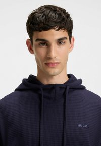 Granatowy hoodie z teksturowanym, waffle knit designem, z kapturem na sznurku i małym haftowanym logo na klatce piersiowej.