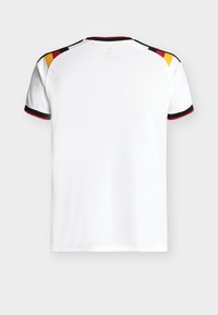 Vue arrière d'un maillot de sport blanc avec des accents noirs, rouges et jaunes sur les épaules, et des bordures noires et rouges aux poignets des manches.