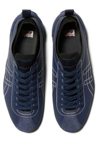 Navy blue athletic shoes with textured fabric, contrasting white stitching, lace-up design, and cushioned interior. Features a pull tab at the heel.