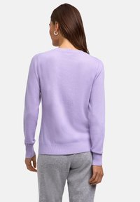 Maglione a maglia viola con collo e polsini a coste, caratterizzato da una texture morbida. Indossato con pantaloni grigi, mostra la vista posteriore.