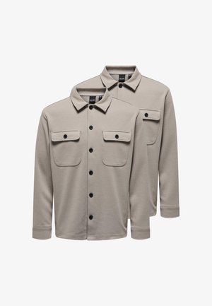 Deux chemises beiges à manches longues, boutonnées, avec des cols et des poches poitrine, affichées superposées sur un fond blanc.