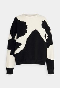 Pull en tricot noir et blanc à coupe ample, présentant des motifs abstraits audacieux, des poignets côtelés et un col rond.