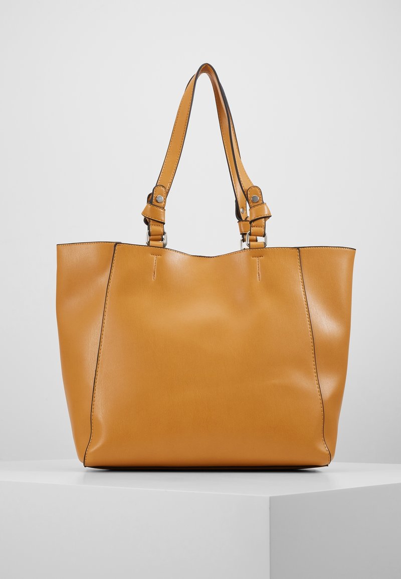 Světle hnědá kabela z hladké kůže, ramenní popruhy s stříbrným kováním a strukturovaný design. Minimalistická bez viditelných vzorů.