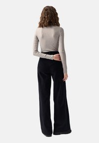 Szary, długi rękaw top połączony z czarnymi, sztruksowymi spodniami z szerokimi nogawkami, które wyróżniają się gładką teksturą i wysokim stanem.