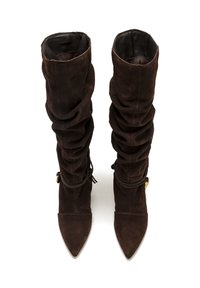 Botas de ante marrón hasta la rodilla con un diseño arrugado, punta afilada y forro de cuero. Presentan un acento atado en el tobillo y detalles en dorado.