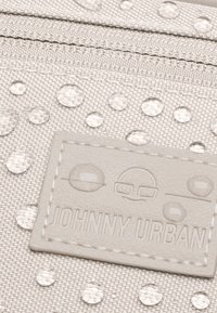 Világosszürke anyagú tasak, kiemelkedő pötty mintázattal és vízcseppekkel, texturált logóval, amelyen a "JOHNNY URBAN" felirat látható.