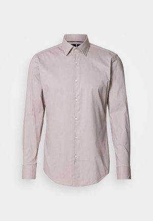 Cămașă roz pal cu mânecă lungă, cu guler, având nasturi albi și o textură netedă, țesută. Cămașa are un tiv curbat.