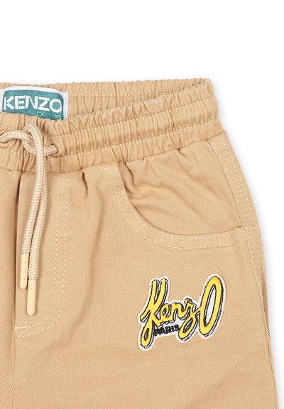Pantaloni corti in cotone beige con cintura elastica, coulisse, tasche laterali e logo "Kenzo" ricamato in giallo e nero. Tessuto testurizzato.