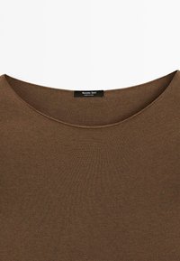 Braunes, strukturiertes Strickshirt mit weitem Ausschnitt, das ein kleines schwarzes Etikett mit der Aufschrift "Massimo Dutti" trägt und "Hergestellt in China" angibt.