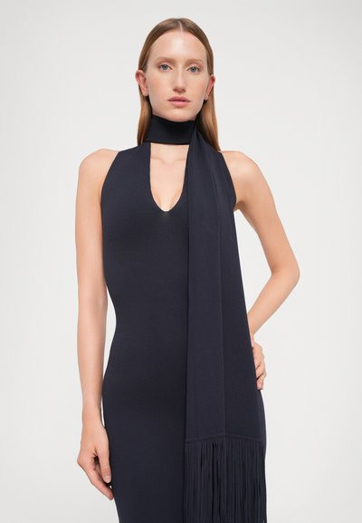 Rochie slim-fit, fără mâneci, de culoare bleumarin, cu decolteu în V adânc și guler înalt. Rochia are o eșarfă lungă, cu franjuri, care se extinde din guler.