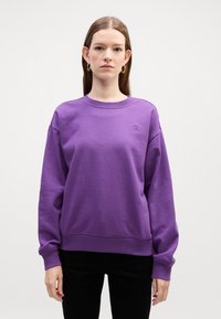 Felpa viola con maniche lunghe, polsini e orlo a coste, che presenta un logo discreto sul petto. Tessuto morbido e vestibilità rilassata.