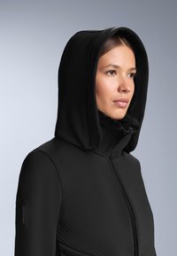 Czarna kurtka z kapturem, z teksturowanym wzorem na korpusie i sztucznym futerkiem przy kołnierzu. Logo Recco na rękawie.