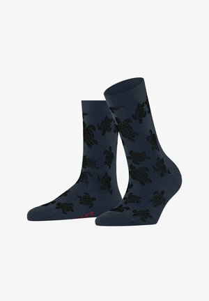 Marinefarbene Socken mit einem Schildkrötenmuster in Schwarz. Gerippte Bündchen, mittellang, aus Baumwollmischung. Rote Textakzente auf der Unterseite.