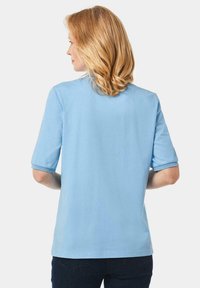 Hellblaues Baumwoll-T-Shirt mit kurzen Ärmeln, rundem Halsausschnitt und hochgerollten Ärmeln. Weicher Stoff, schlichtes Design, keine sichtbaren Muster.