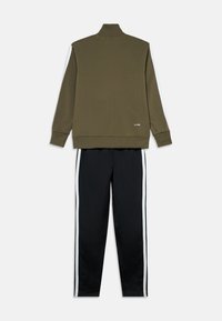 Olivově zelená bunda na zip s vysokým límcem a bílými proužky po stranách, spárovaná s černými kalhotami s bílými proužky po stranách. Měkká látka, volný střih.