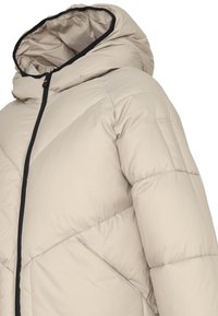 Giacca puffer beige con texture a costine, cappuccio e zip nera. Presenta motivi di cucitura geometrici e una tasca laterale.