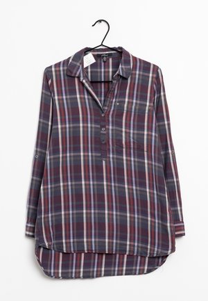 Langärmeliges kariertes Hemd in Schattierungen von Lila, Blau und Grau, mit Kragen, Brusttasche, Knöpfen und abgerundetem Saum, aufgehängt an einem schwarzen Bügel.