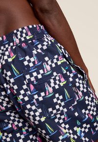 Marine zwemshorts met een zeilbootpatroon in felle kleuren, voorzien van een elastische tailleband en een achterzakdetail.