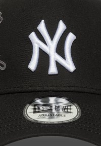 Casquette de baseball noire avec logo « NY » brodé en blanc, taille réglable, visière plate et étiquette circulaire New Era au dos.